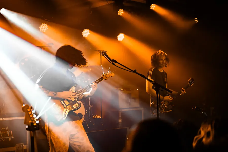 Gitarrist mit Locken im warmen Scheinwerferlicht – Fomies live im Salzhaus Winterthur, 2025