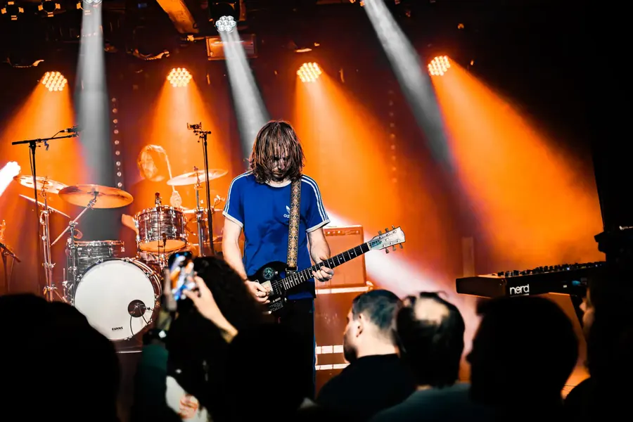 Gitarrist im blauen Shirt vor dem Schlagzeug, Gegenlicht – Fomies live im Salzhaus Winterthur, 2025