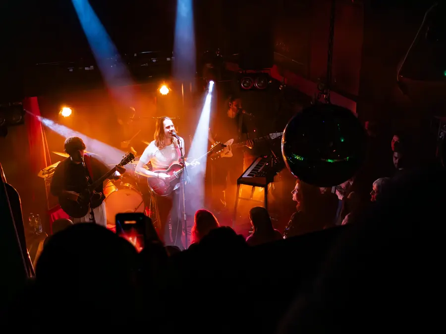 Sängerin mit Gitarre im orangen und blauen Bühnenlicht – Marlene Käthe live im Salzhaus Winterthur, 2025