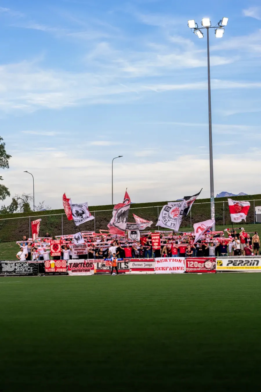 FCW-Fans mit Fahnen im Gästesektor unter blauem Himmel – FC Stade Nyonnais gegen FC Winterthur, 1. September 2026