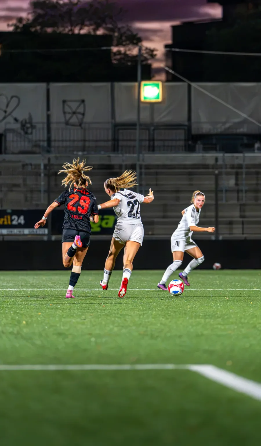 Mehrere Spielerinnen sprinten in der Abenddämmerung zum Ball – FC Wil gegen FC Winterthur Frauen, 9. September 2026
