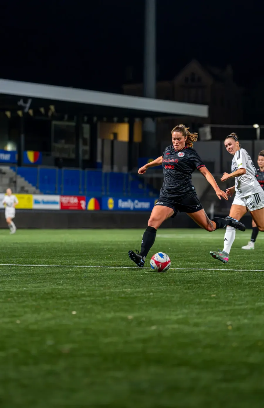FCW-Spielerin in Schwarz am Ball, eine Wil-Spielerin in Weiss verfolgt sie – FC Wil gegen FC Winterthur Frauen, 9. September 2026