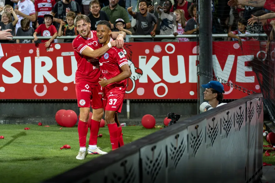 Zwei FCW-Spieler feiern ein Tor vor der Sirupkurve, rote Ballone auf dem Rasen – FC Winterthur, Heimspiel auf der Schützenwiese