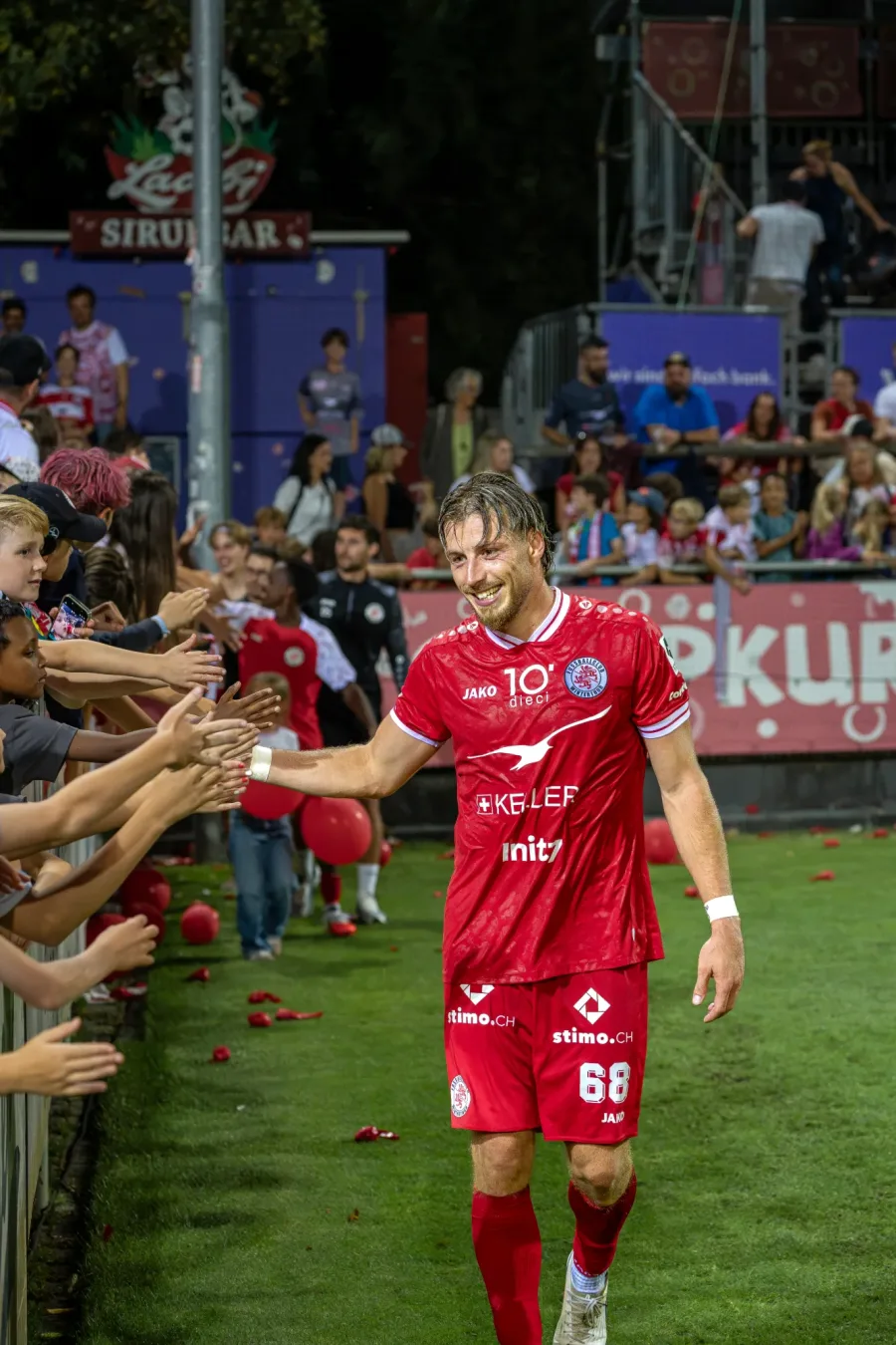 FCW-Spieler mit der Nummer 68 klatscht mit den Fans an der Bande ab – FC Winterthur, Heimspiel auf der Schützenwiese